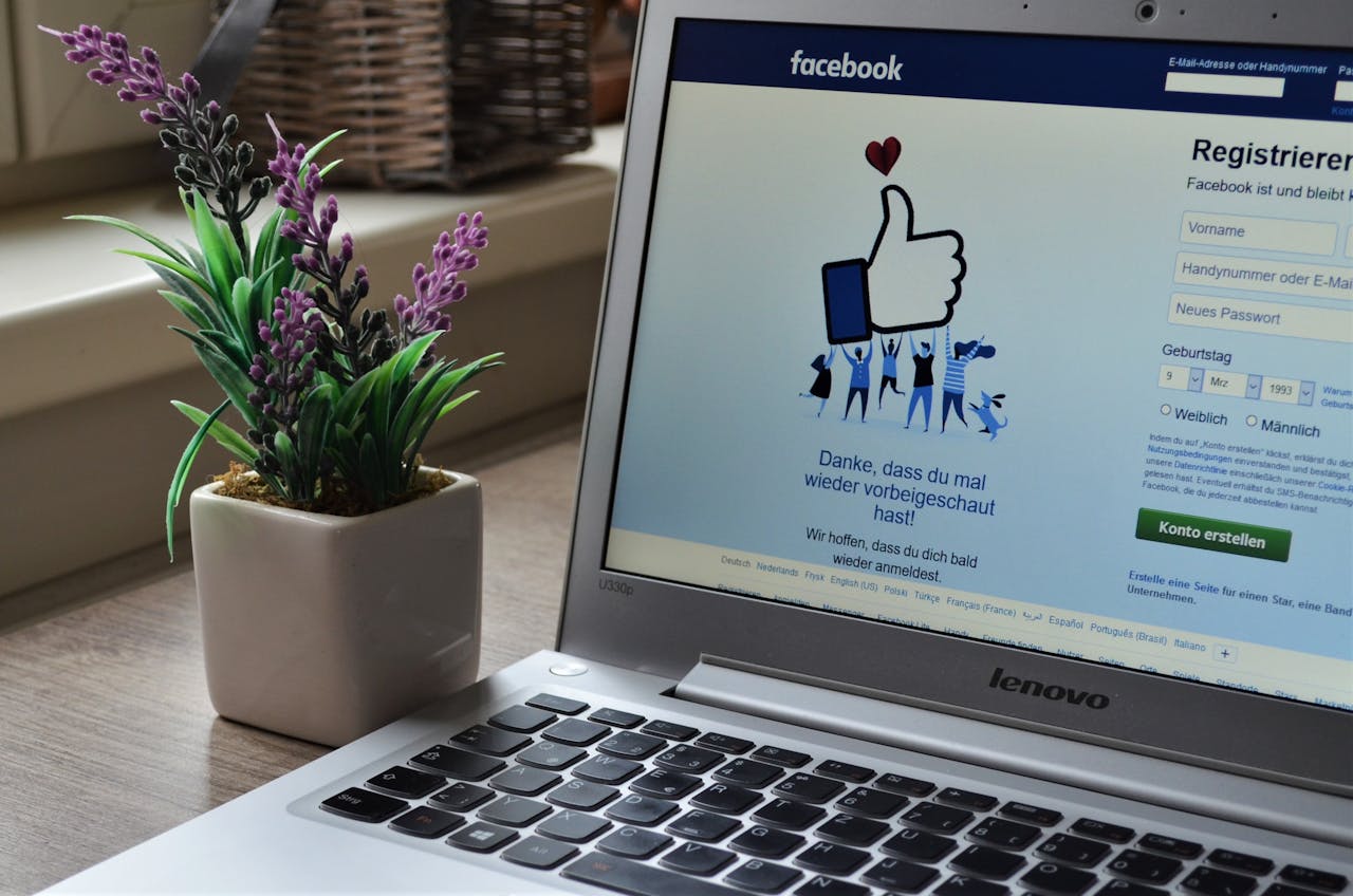 about-us-02 A Lenovo laptop displaying Facebook login beside a lavender plant indoors.